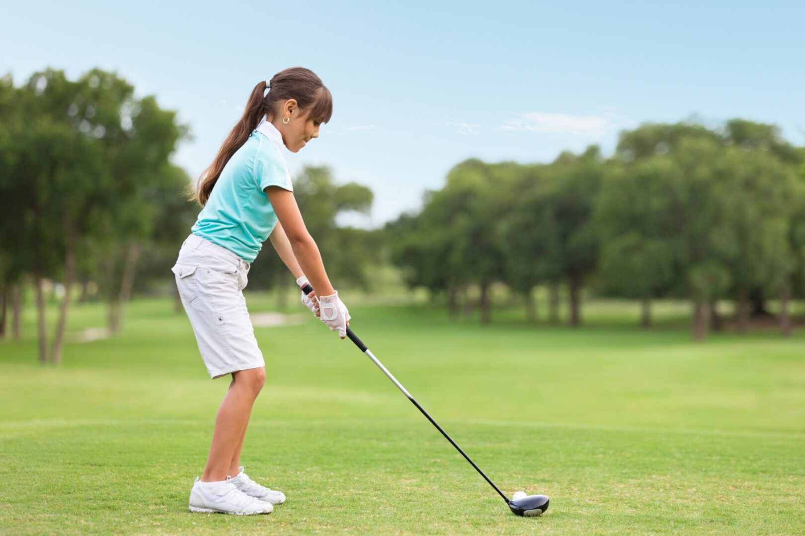 Girl teeing off on lush green