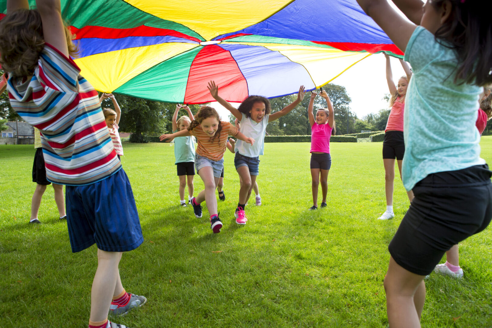 Children playing under colorful parachute outdoors